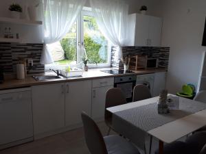 a kitchen with white cabinets and a table and a window at Mistel Apartman in Bodensdorf