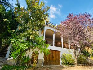 Casa blanca con puerta de madera y árboles en Barranco de la Salud, en Laroles