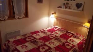 Schlafzimmer mit einem Bett mit einer roten und weißen Decke in der Unterkunft Perthuis 11D - Appartement 5 pers - Chatel Reservation in Châtel