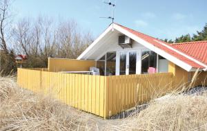 a house with a yellow fence in the grass at Gorgeous Home In Hvide Sande With Wifi in Havrvig