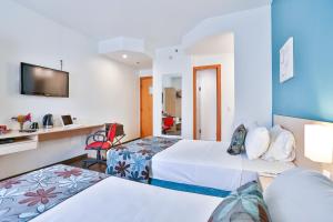 a hotel room with two beds and a tv at Comfort Hotel Joinville in Joinville