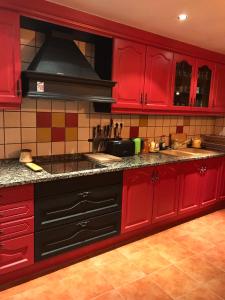 cocina roja con armarios rojos y fogones en Casa Rustica Cabanes, en Ordino