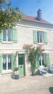 una casa con persianas verdes y flores delante de ella en Wisteria Cottage, en Fleurines