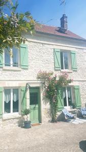 ein Haus mit grünen Fensterläden und Blumen davor in der Unterkunft Wisteria Cottage in Fleurines