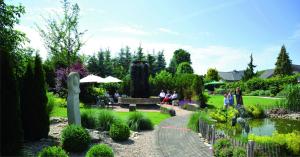 un jardin avec des personnes assises sur des bancs et un étang dans l'établissement Kurhotel Grüttner mit eigenem Sole Thermal Schwimmbad 32 Grad und Saunalandschaft, à Erwitte