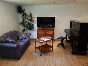 a living room with a couch and a table and a piano at 4 Sterne Souterrain Apartment Alt-Mariendorf in Berlin