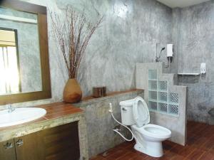 a bathroom with a toilet and a sink and a mirror at Pai My Guest Resort - SHA Plus in Pai