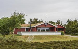 a red house with a white fence in front of it at Holiday Home Ringvejen Rømø Iii in Rømø