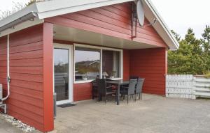 a red house with a table and chairs on a patio at Holiday Home Ringvejen Rømø Iii in Rømø