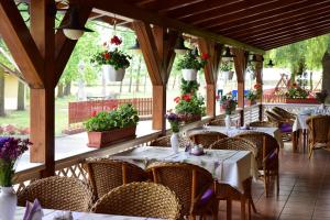 un comedor con mesas, sillas y flores en Hotel Bíbic és Tüskevár Étterem és Horgásztó en Nyíregyháza