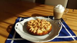 a pastry on a plate next to a glass of coffee at Wellness Ferienwohnung mit Bademantelgang zur Therme in Bad Griesbach