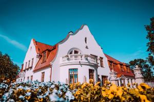 a white house with a red roof at Bahnhofs hotel in Alūksne