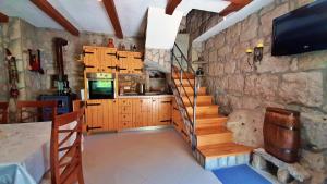 Habitación con pared de piedra, escalera y TV. en Holiday Home with a Private Pool en Podšpilje