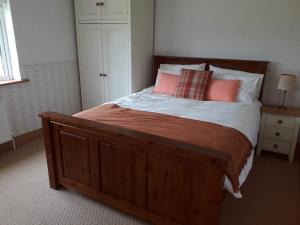 1 dormitorio con cama de madera y 2 almohadas en Wellfield Farmhouse en Tipperary