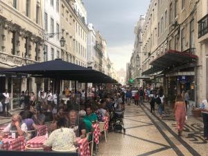 un gruppo di persone seduti ai tavoli in una strada di città di Lisbon Center Rua Augusta Modern Art Apartment a Lisbona