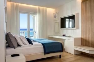 Schlafzimmer mit einem Bett, einem TV und einem Fenster in der Unterkunft Hotel Cavalieri Palace in Lido di Jesolo