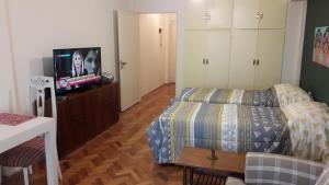 Viva San Martín, Apartamento Luminoso في بوينس آيرس: غرفة نوم صغيرة بها سرير وتلفزيون