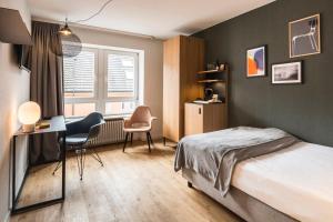 1 dormitorio con 1 cama, escritorio y sillas en Genusshotel Krone & Roadtrips bei Basel, en Inzlingen