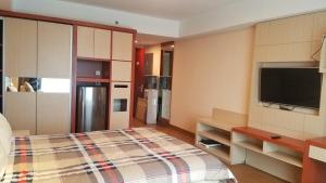 a room with a kitchen with a bed and a tv at Lavenderbnb Room 10 at Mataram City Apartment in Yogyakarta