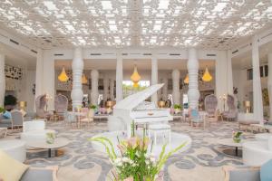 a grand lobby with a white piano and chairs at Hotel Farah Tanger in Tangier