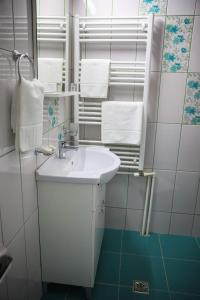 a white bathroom with a sink and towels at Pensiunea Lucian in Bălţaţi