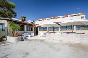 un bâtiment avec des tables et des parasols devant lui dans l'établissement Albergo Labotte, à Vieste