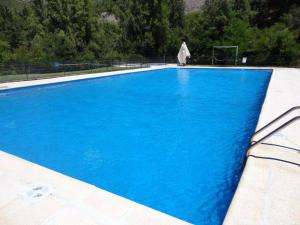 Una gran piscina azul con árboles al fondo. en Cabañas Parque Almendro, en San José de Maipo