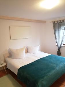 1 dormitorio con cama blanca y manta azul en Ferienhaus "Schleif", en Heiligkreuzsteinach