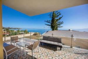 un patio con un banco y sillas y el océano en Appartamento 16 Pax in Villa Francesca Sicily sul mare, en Casteldaccia