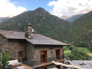 ein Steinhaus mit Bergen im Hintergrund in der Unterkunft Casa Rustica Cabanes in Ordino