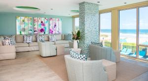 a living room with a couch and chairs and the ocean at One Ocean Resort and Spa in Atlantic Beach