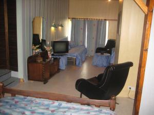 a living room with a tv and a chair and a couch at Auberge Hôtel chambre Tout Confort B-B et Restaurant Les Colombes in Sugny