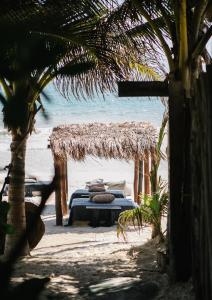 a bed on the beach with a straw canopy at NEST Tulum in Tulum