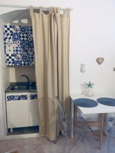 - une cuisine avec un évier, une table et un rideau dans l'établissement CASA VACANZE OCCHI BLU (BEB), à Molfetta