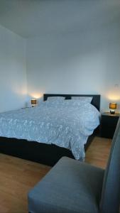 1 dormitorio con 1 cama con colcha blanca y silla en Le Gite du Relais, en Masevaux