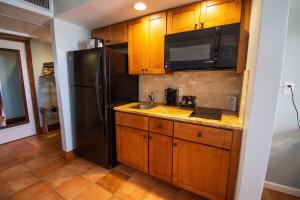 a kitchen with a black refrigerator and wooden cabinets at Vanderbilt Beach Resort in Naples