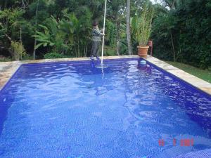 um rapaz com uma mangueira numa piscina azul em Casailhabela em Ilhabela