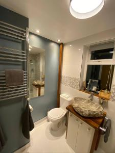 y baño con aseo, lavabo y espejo. en Luxury 5* Home with Secret Garden and Free Parking, en Liverpool