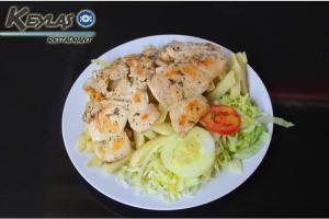 un plato blanco de comida con pollo y verduras en Keylas Hotel, en Ica