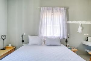 a bedroom with a bed with white sheets and a window at SifnosLiving - Joy in Vathi