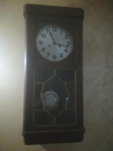 un orologio di legno con un orologio sul muro di Etno selo "Vile Jefimija" a Vranje