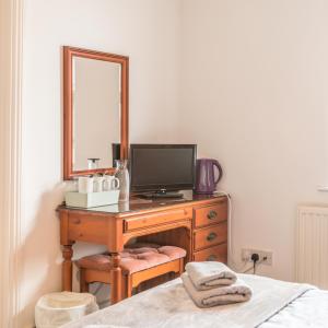 a bedroom with a desk with a television and a mirror at The Wootons Inn in Tintagel