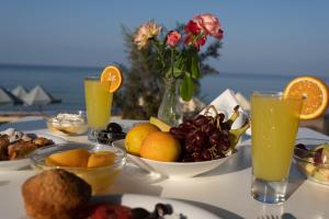 Harmony Hotel في كوروتا: طاولة مقدمة مع أطباق من الفواكه وعصير البرتقال