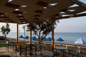 Harmony Hotel في كوروتا: فناء به طاولات وكراسي والشاطئ