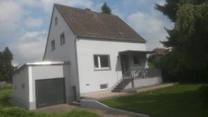 a white house with a gate and a garage at Ferienhaus Eifel-Charme in Birgel