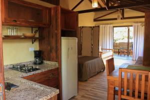a kitchen with a refrigerator and a table in a room at Complexo de Pousadas Caraguatá in Ilha do Mel