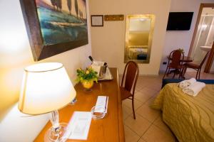 Zimmer mit einem Tisch mit einer Lampe und einem Bett in der Unterkunft Lion's Hotel in Falerna