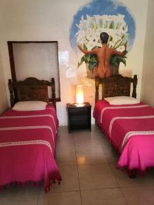 Cette chambre comprend 2 lits et une statue sur le mur. dans l'établissement Hostal Oaxaca Magic, à Oaxaca
