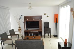 sala de estar con TV de pantalla plana y sillas en Departamentos en Playa La Isla, en Punta Hermosa