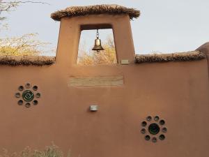 una campana colgando del lateral de un edificio en Hostal y Cabañas Renta House San Pedro, en San Pedro de Atacama